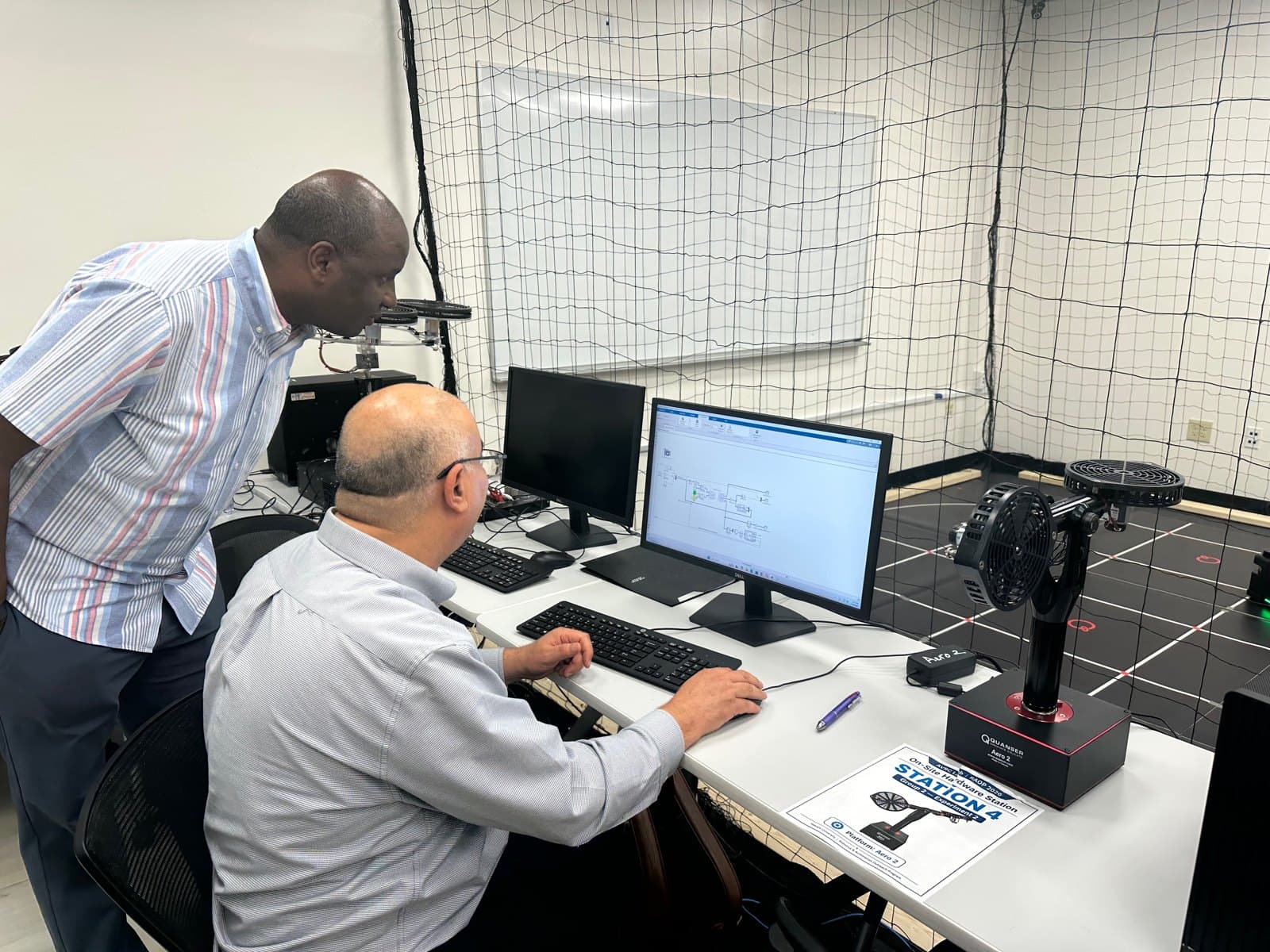 Educators discuss an Aero 2 setup beside its computer interface.