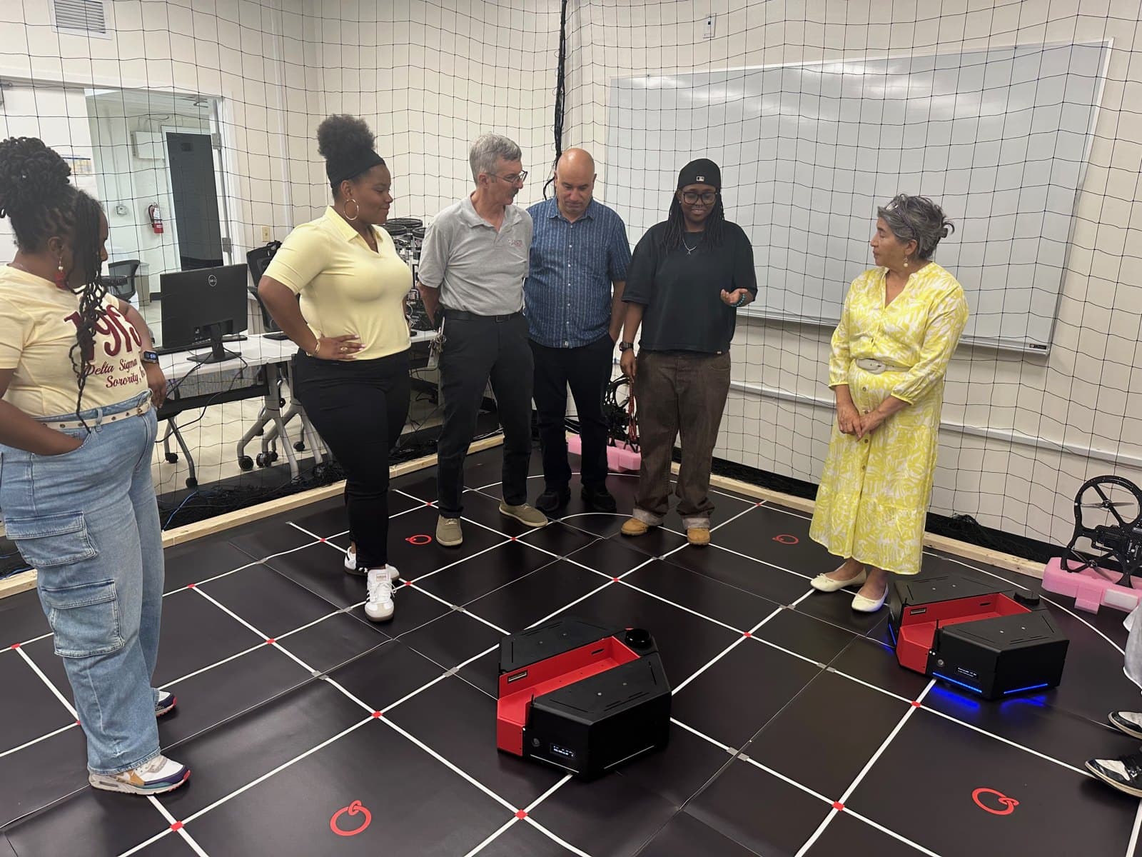 Six RAOP 2026 participants and facilitators, including Fadel Lashhab, beside mobile robotics platforms